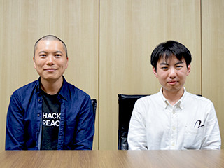 椅子に座り笑顔の鈴木氏と上司である大谷氏の写真