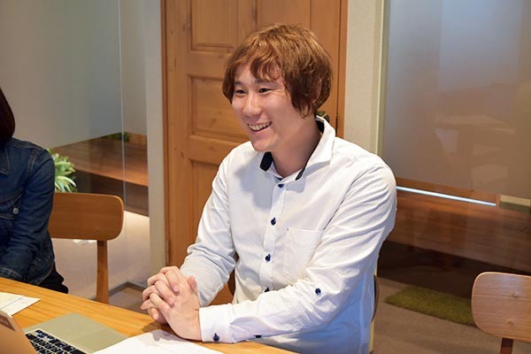 笑顔で最初の就職先での経験を語る田中氏の写真