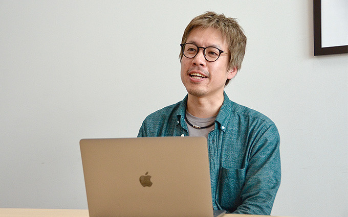 ノートパソコンを前に自身の働き方について語る岡田氏の写真