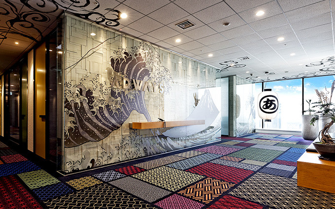 葛飾北斎「冨嶽三十六景 神奈川沖浪裏」をイメージして彩られた壁に会社のロゴが飾られ、和モダンなデザインが成されている、株式会社アドウェイズのエントランスの写真